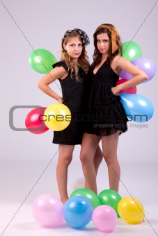 two beautiful women, with colored ballons, studio shot.