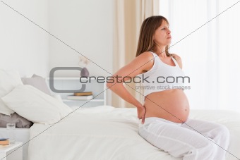 Beautiful pregnant female having a back pain while sitting on a 