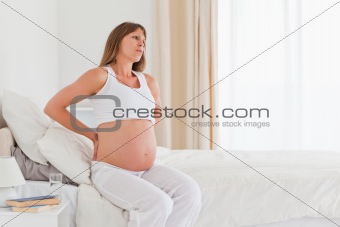 Attractive pregnant female having a back pain while sitting on a