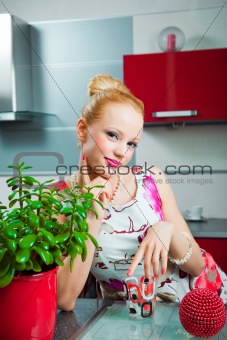 Blond girl with glass in interior of kitchen