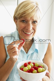 Middle Aged Woman Eating A Bowl Of Fruit