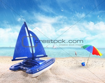 Toy sailboat in sand with beach scene