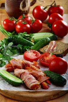 Sausages wrapped in bacon with vegetables and herbs.