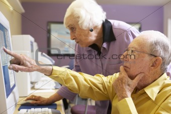 Senior woman helping senior man use computer