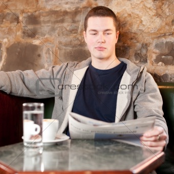 Morning coffee and news - Handsome young man reading newspaper 