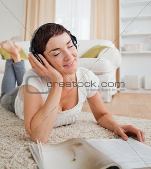 Portrait of a delighted woman with a magazine enjoying some musi