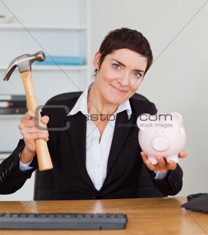 Young office worker breaking a piggybank with a hammer