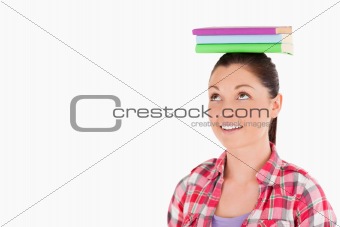 Attractive female holding books on her head while standing