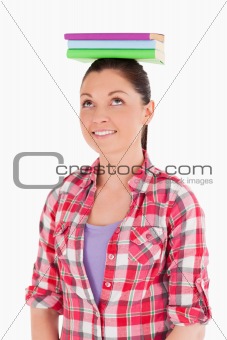 Beautiful female holding books on her head while standing