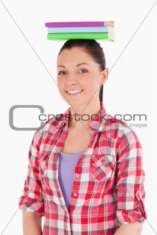 Good looking female holding books on her head while standing