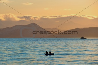 Fishermen by a boat in an evening bay