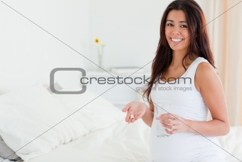 Beautiful pregnant woman holding a glass of water and pills