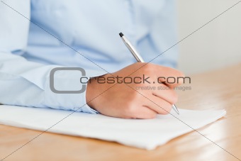 Woman writing on a sheet of paper while sitting