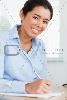 Good looking woman writing on a sheet of paper while sitting
