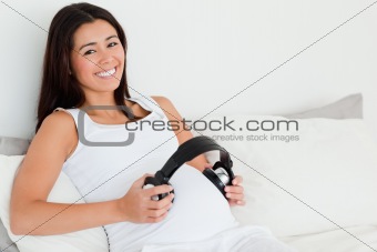 Frontal view of an attractive pregnant woman putting headphones 