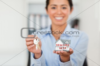 Attractive woman holding keys and a miniature house
