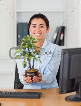 Beautiful woman holding a plant while looking at the camera