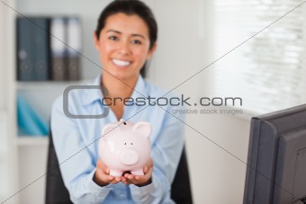 Attractive woman holding a piggy bank while looking at the camera