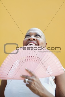 mature african woman with fan, smiling 