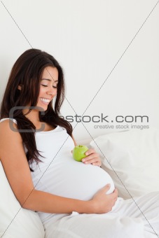 Good looking pregnant woman holding an apple on her belly