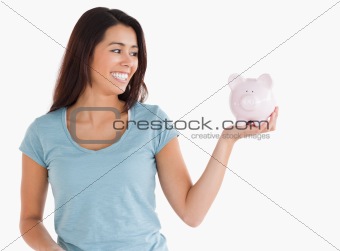 Good looking female holding a piggy bank