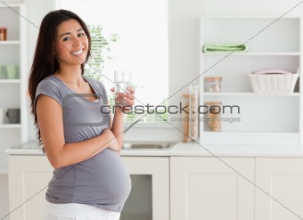 Good looking pregnant woman holding a glass of water 