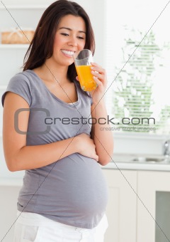 Attractive pregnant woman drinking a glass of orange juice 