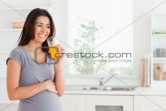 Good looking pregnant woman drinking a glass of orange juice 