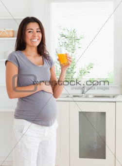 Gorgeous pregnant woman holding a glass of orange juice