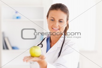 Smiling doctor with stethoscope holding an apple