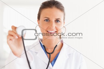 gorgeous brunette doctor showing stethoscope looking into the camera