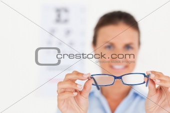 Portrait of a brunette eye specialist handing out glasses smiling into the camera