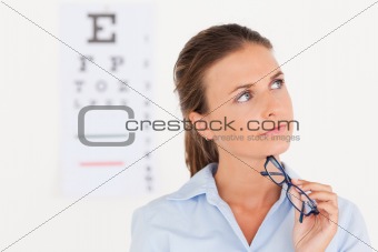 Thinking eye specialist holding glasses
