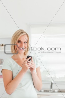 Cute woman with a mobile looking into the camera