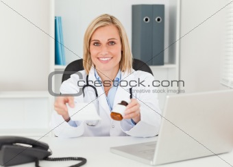Charming doctor holding prescription and medicine to camera
