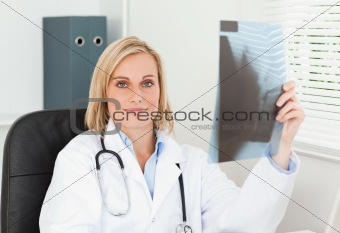 Charming doctor holding x-ray looks into camera