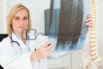 Serious doctor looking at x-ray looks into camera