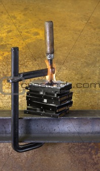 clamp pressing on stack of burning hard drives