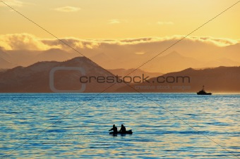 Fishermen by a boat in an evening bay