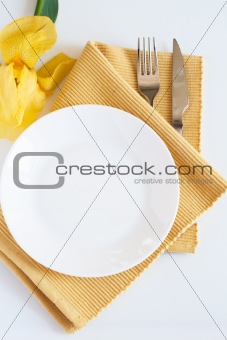 Fork, knife, plate and yellow iris flower