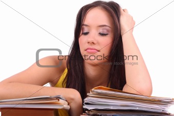 Stressed young woman sitting at a table among books and papers o
