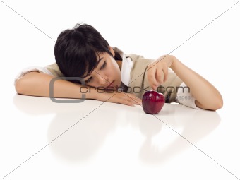 Melancholy Mixed Race Young Adult Female Sitting at White Table with Apple Isolated on a White Background - Focus is on the Apple.
