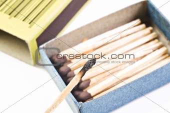 Open box of matches with one match burning