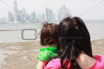 Mother indicates her baby something interesting in sea 