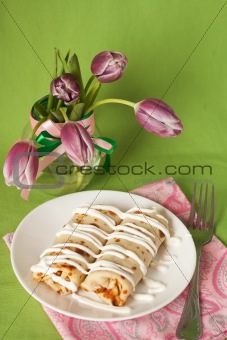Pancakes with sour cream for breakfast and a vase of purple tulips