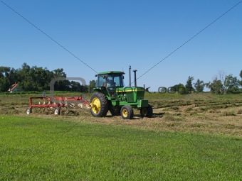 Tractor With Hay Rake Working in a Field