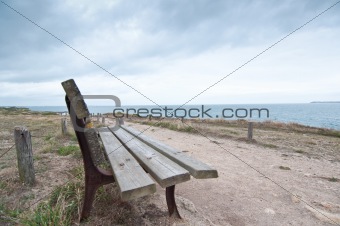 Wooden bench facing the sea on a cloudy day