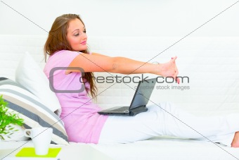Tired beautiful housewife sitting on sofa with laptop
