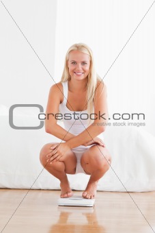 Portrait of a woman squatting on a weighing machine