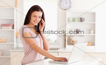 Woman telephoning with hand on laptop